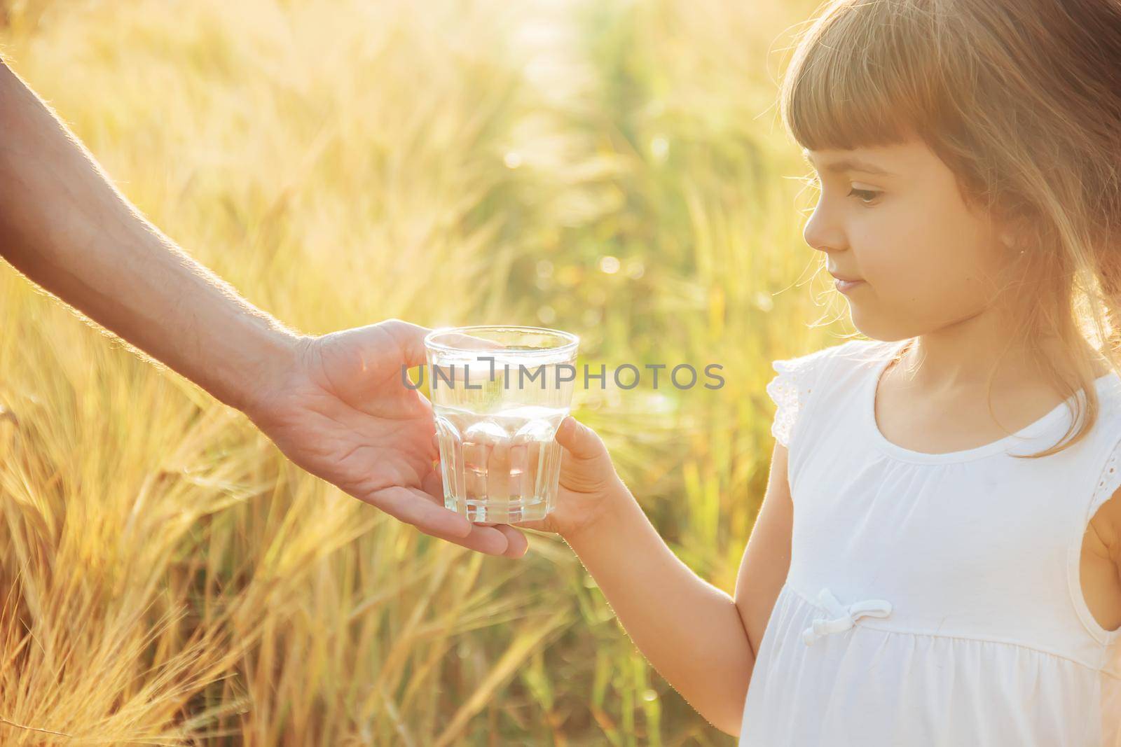 The father gives the child a glass of water. Selective focus.