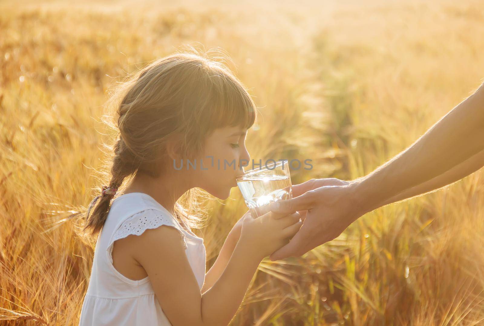 The father gives the child a glass of water. Selective focus.