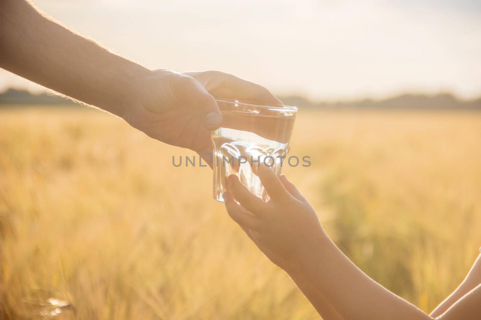 The father gives the child a glass of water. Selective focus.