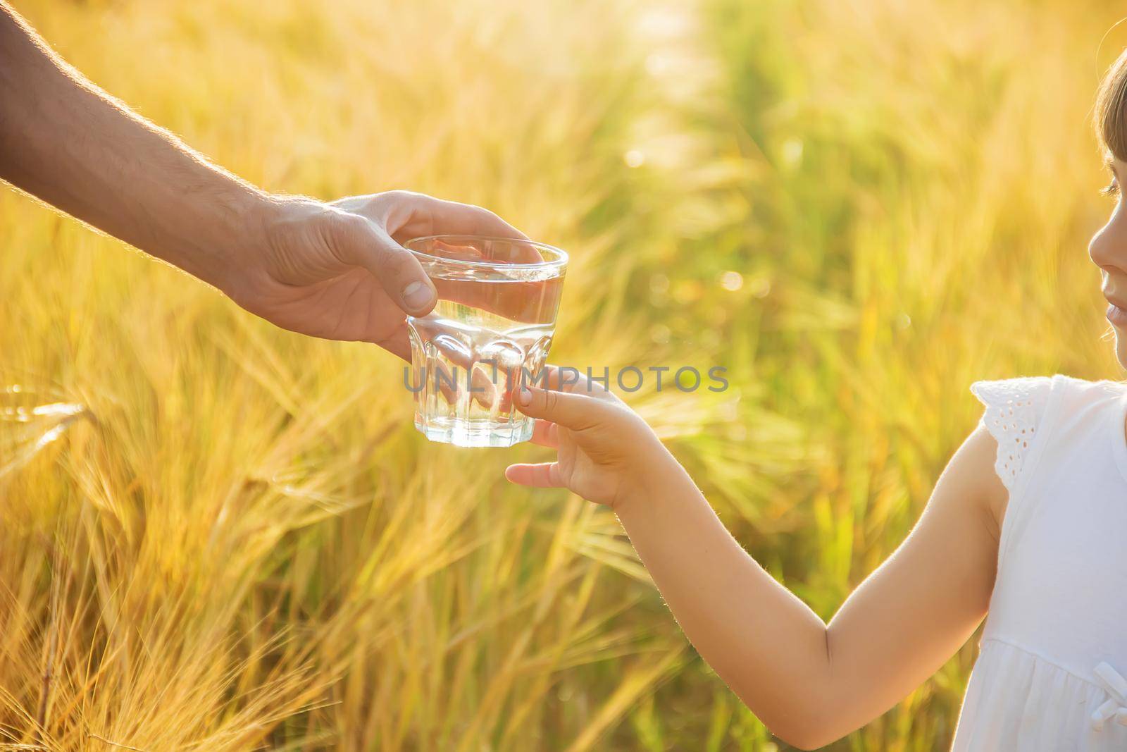 The father gives the child a glass of water. Selective focus.