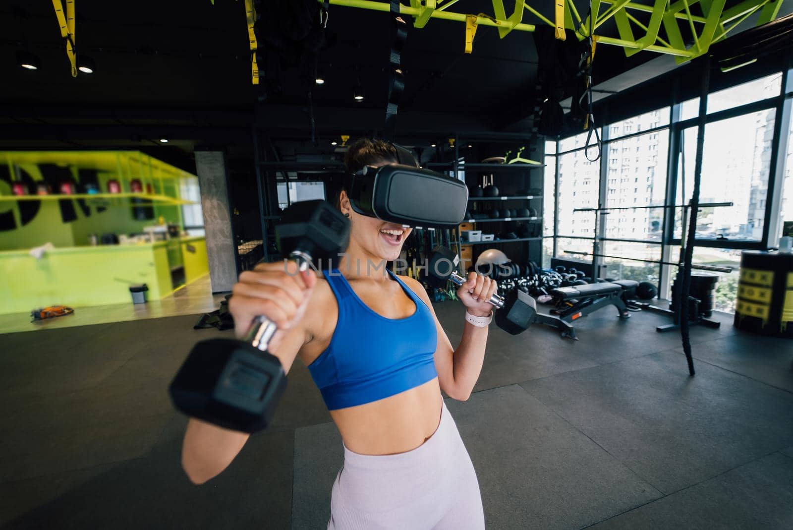 Portrait view of the woman wearing glasses of the virtual reality exercising with dumbbells at gym.