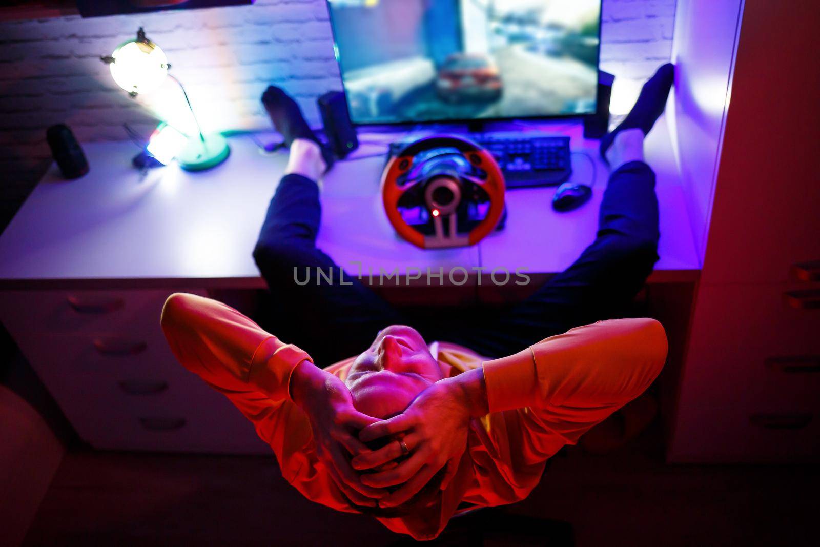 Male gamer playing racing games on the computer. He uses the steering wheel. Emotional game