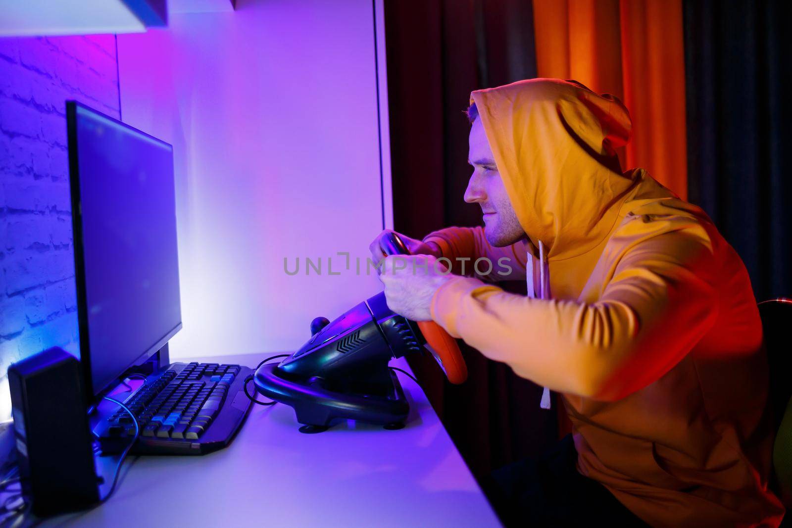 Male gamer playing racing games on the computer. He uses the steering wheel. Emotional game