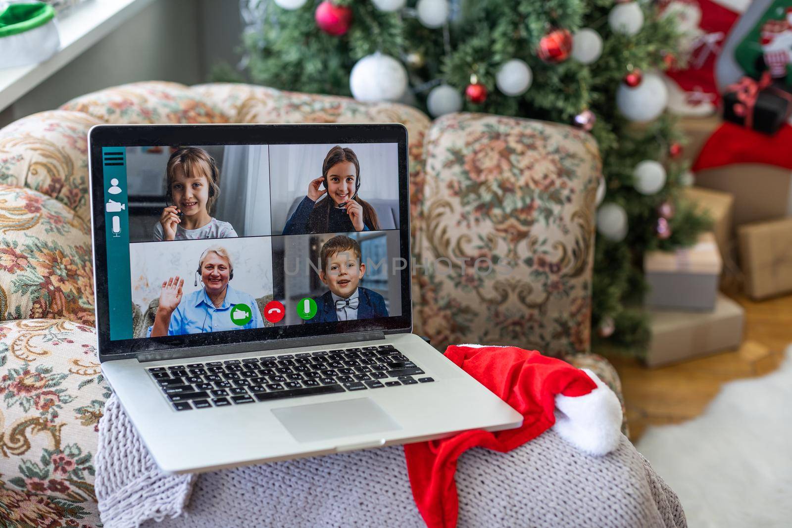 A happy family with a child is celebrating Christmas with their friends on video call using webcam. Family greeting their relatives on Christmas eve online. New normal virtual event