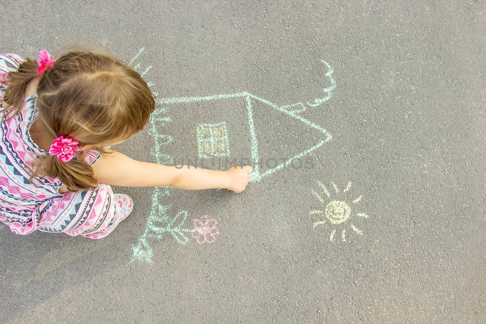 child draws a chalk house. Selective focus. by yanadjana