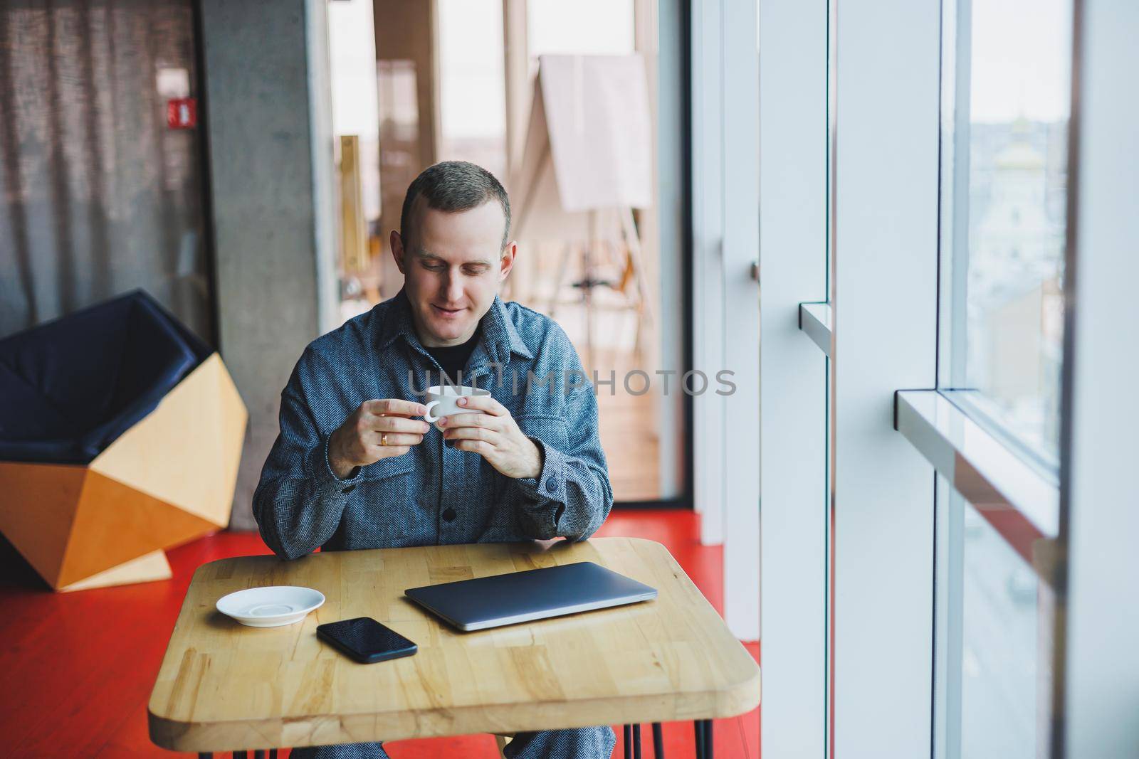 Cheerful IT professional with laptop talking on smartphone to discuss web programming, happy businessman in cafe drinking coffee. freelancer by Dmitrytph