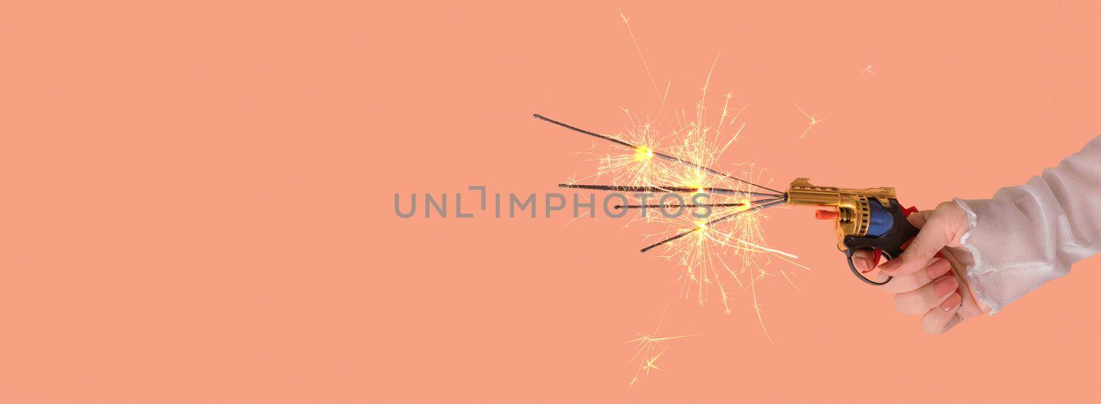 Banner with toy gun with sparkles in a female hand. Festive minimal creative christmas composition by ssvimaliss