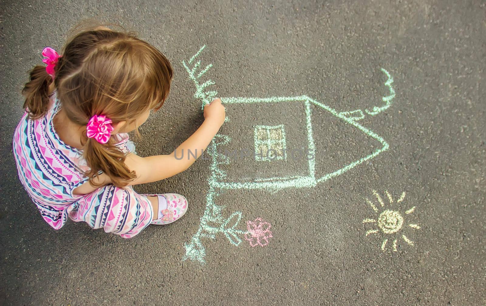 The child draws the house with chalk on the asphalt. Selective focus. draw.