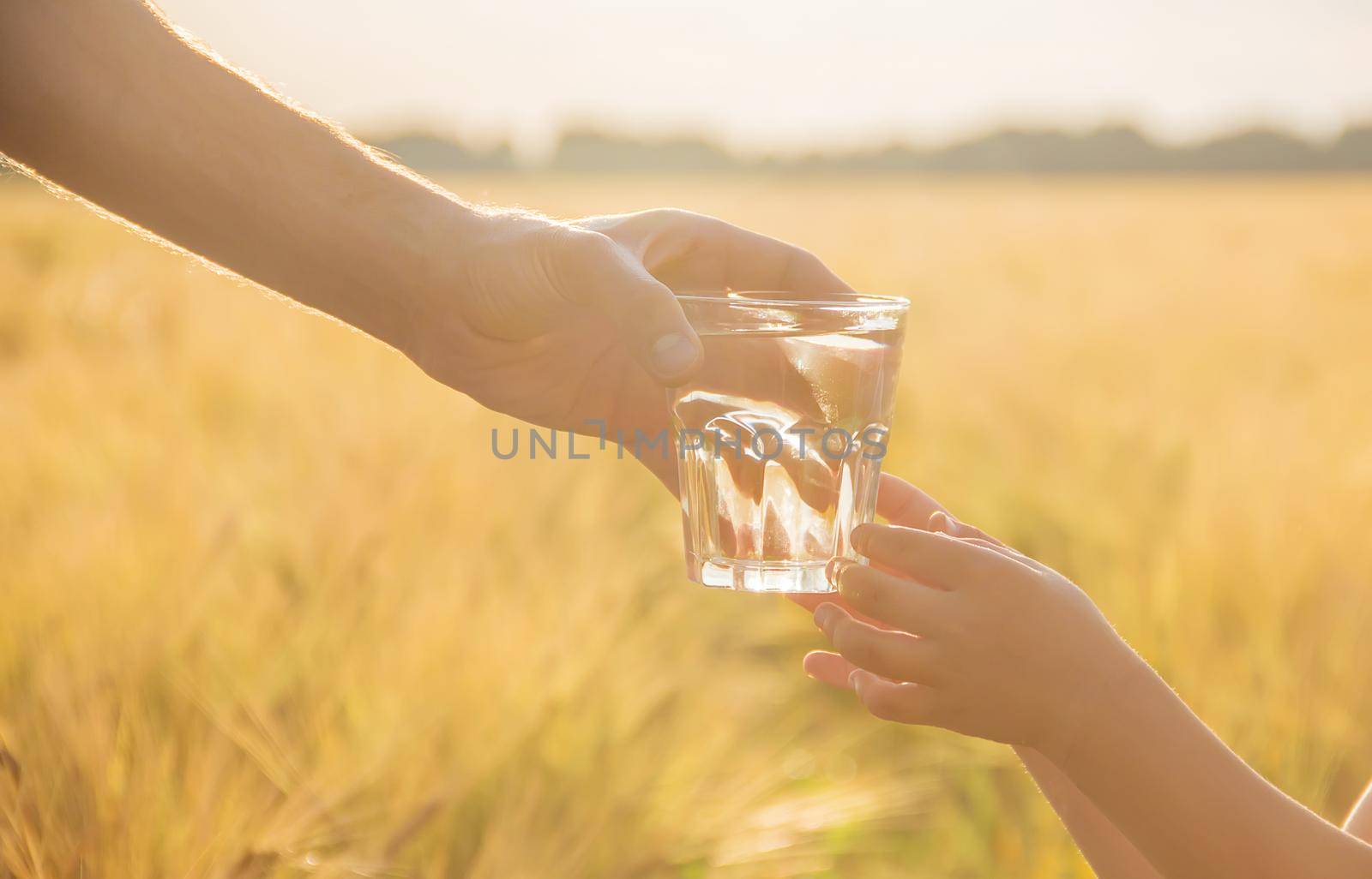 The father gives the child a glass of water. Selective focus. by yanadjana