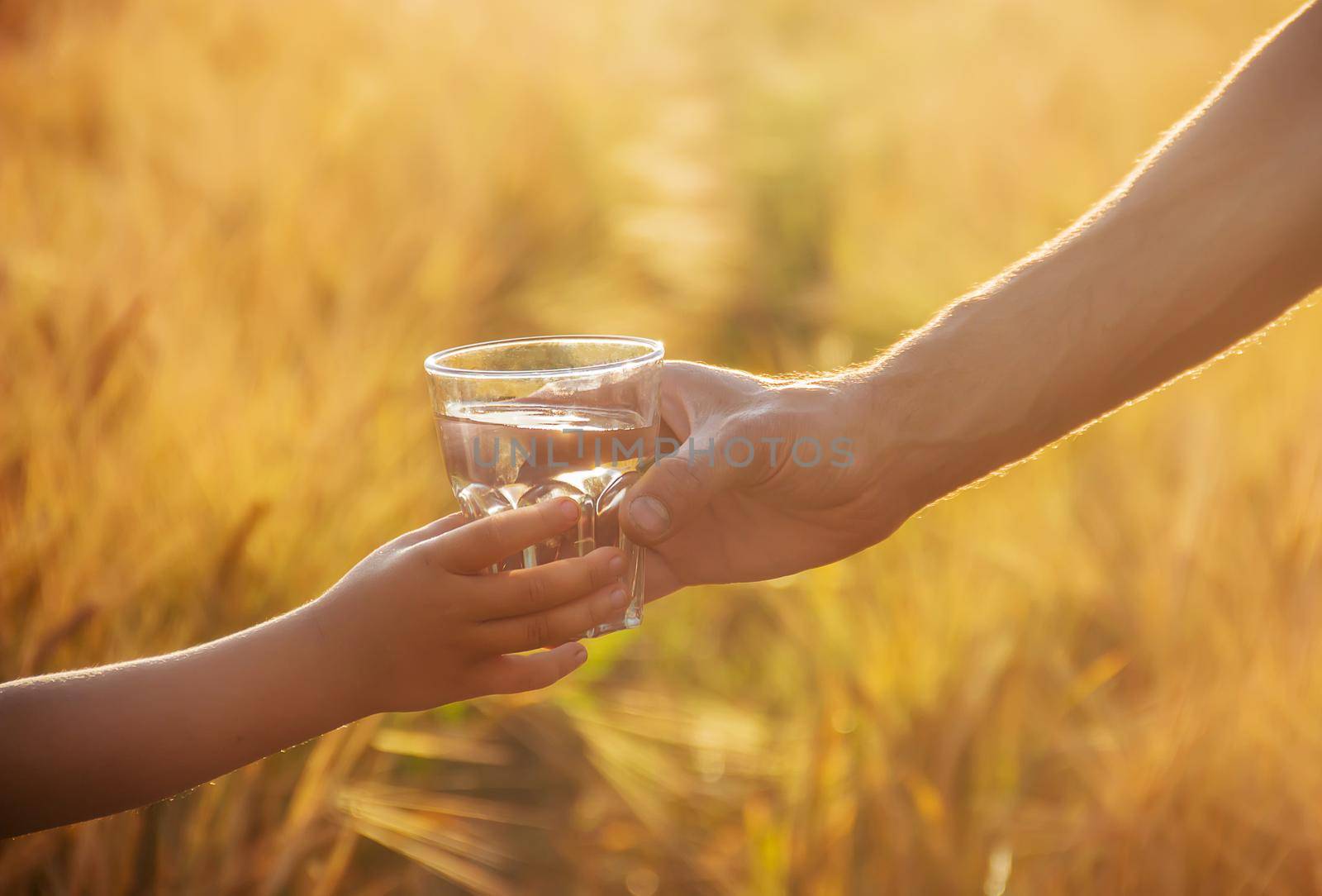 The father gives the child a glass of water. Selective focus. by yanadjana