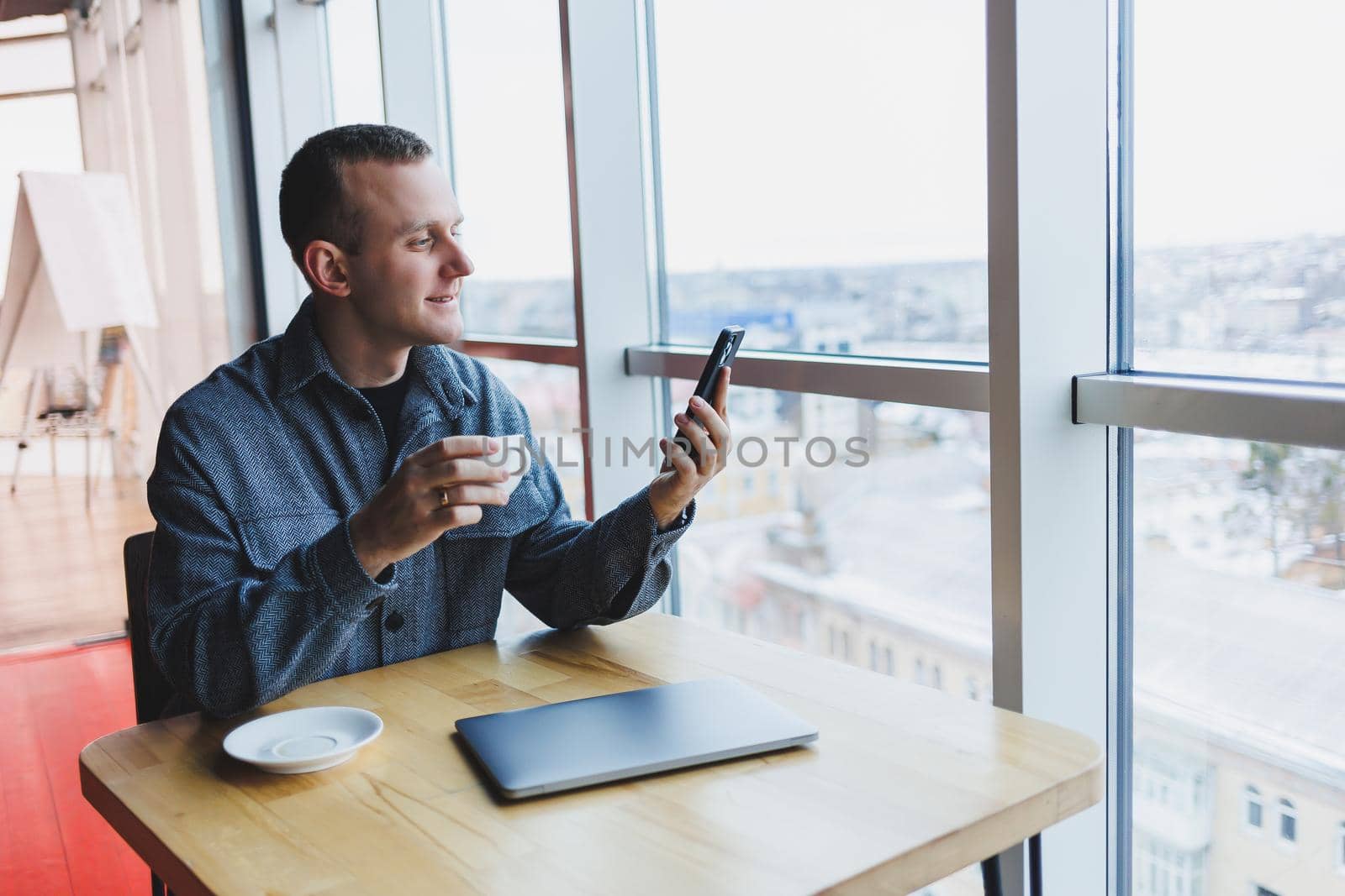 Happy smiling male manager sitting in cafe using mobile phone gadget, ordering delivery service via online app, free 4g wireless network in cafe, cheerful freelancer texting on mobile phone