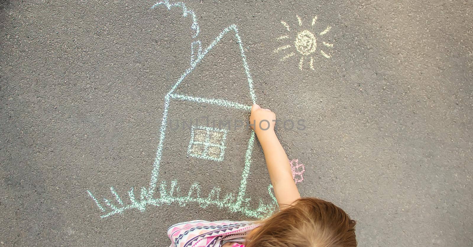 child draws a chalk house. Selective focus.