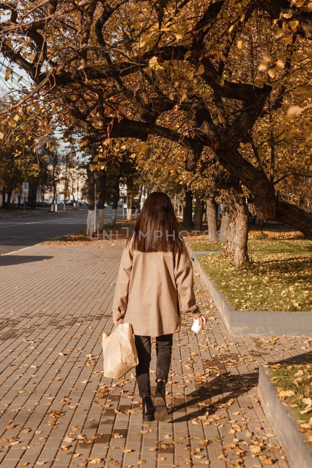 A stylish brunette woman walks around the autumn city. The season is autumn.