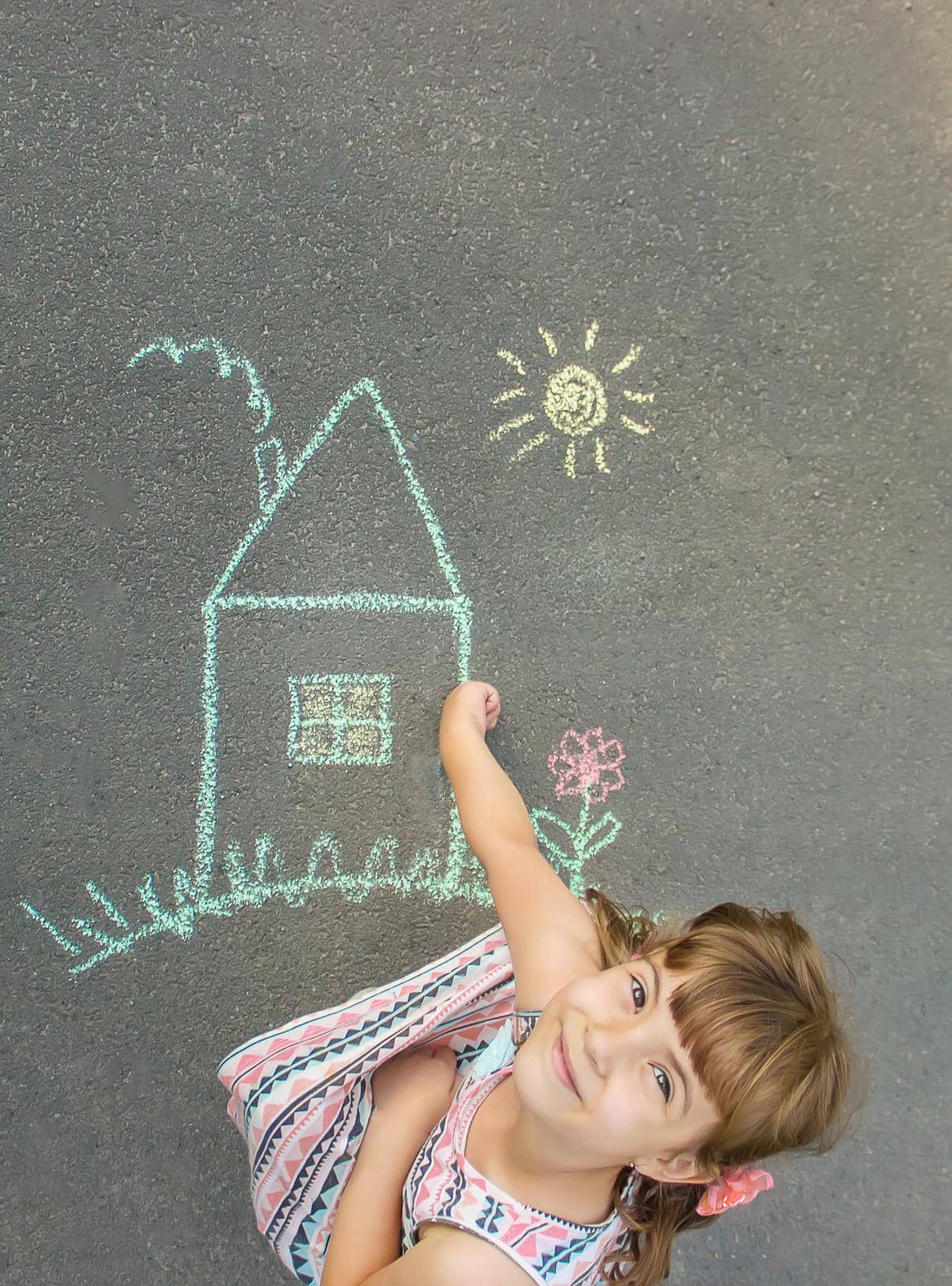 child draws a chalk house. Selective focus.