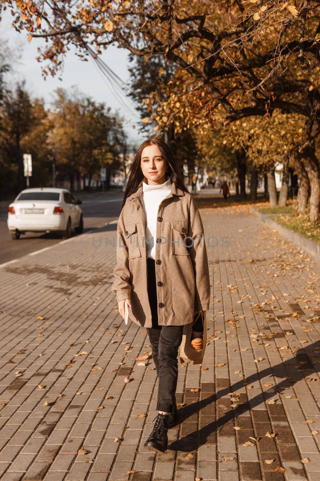 A stylish brunette woman walks around the autumn city. The season is autumn.