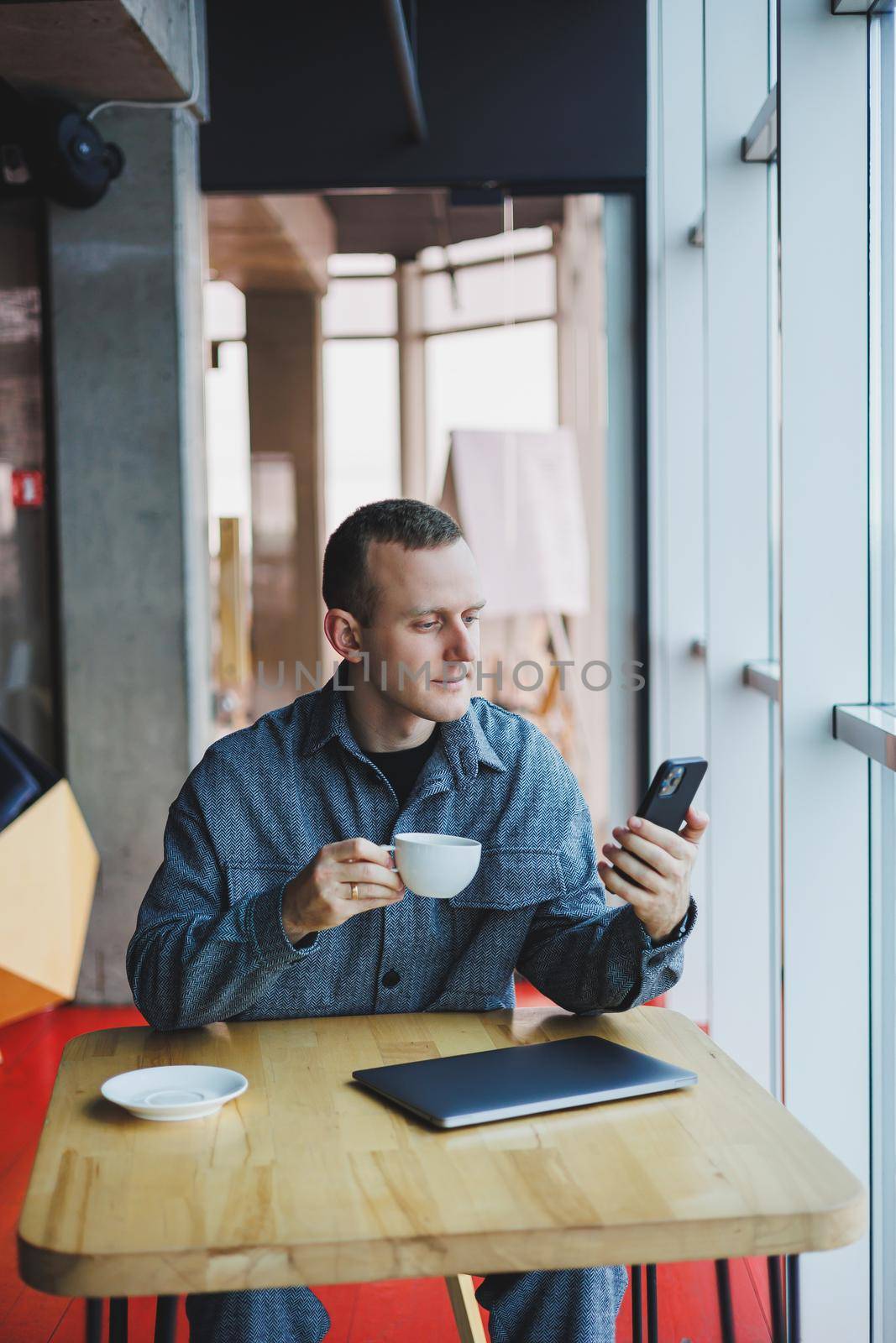 Happy smiling male manager sitting in cafe using mobile phone gadget, ordering delivery service via online app, free 4g wireless network in cafe, cheerful freelancer texting on mobile phone