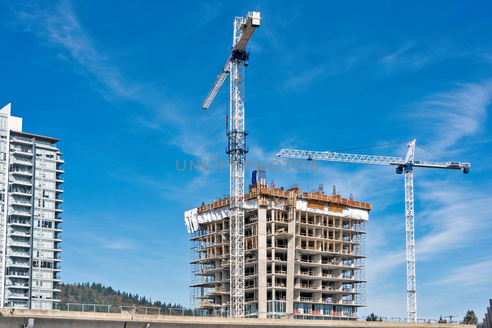 Concrete high rise residential building under constraction on blue sky background