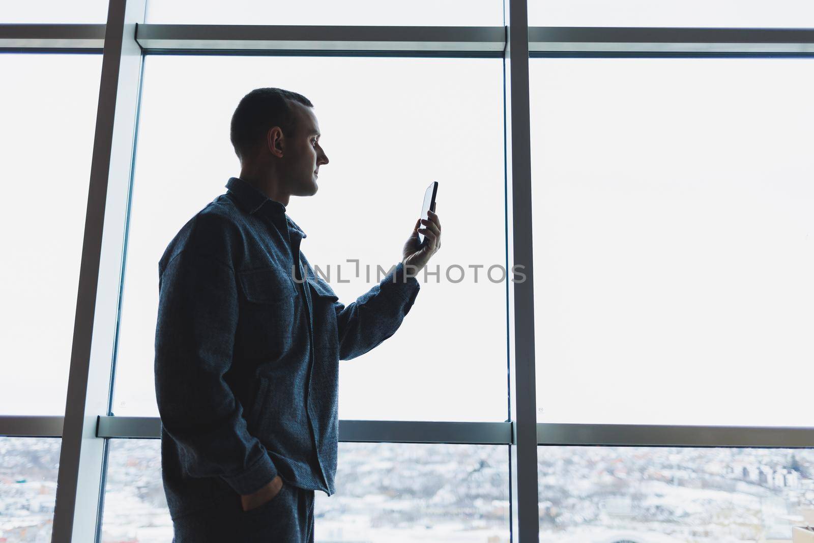Young business man holding a phone. In an office or business center against the background of large windows of a skyscraper. Work and career, concept