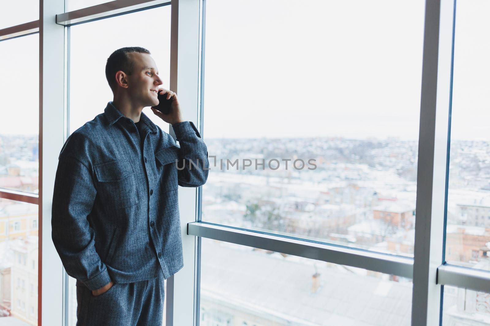 Young business man holding a phone. In an office or business center against the background of large windows of a skyscraper. Work and career, concept