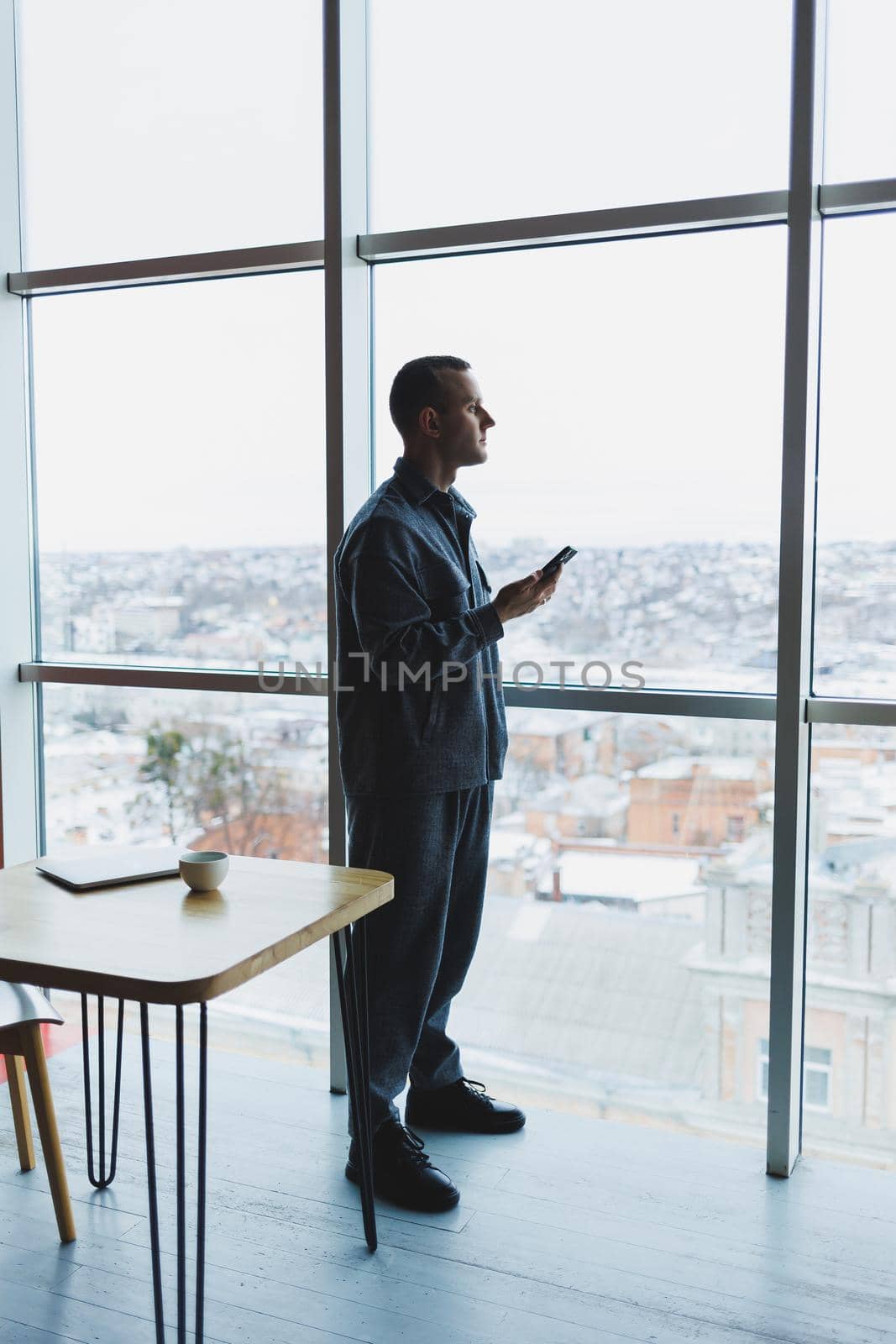 Young business man holding a phone. In an office or business center against the background of large windows of a skyscraper. Work and career, concept