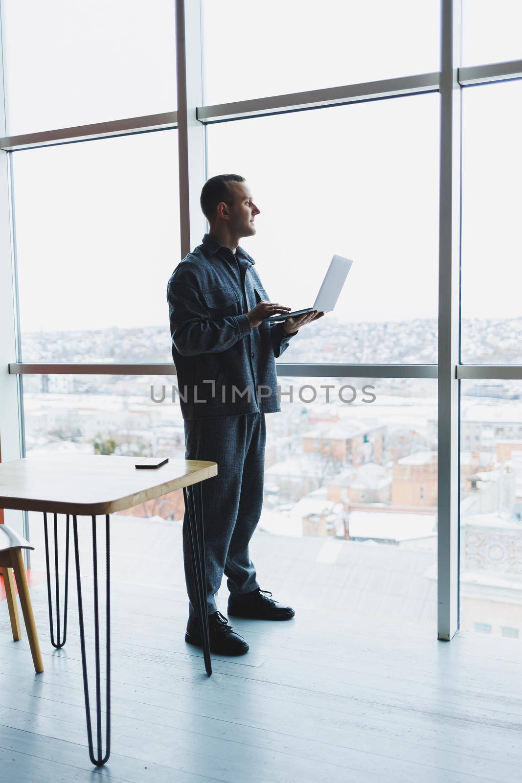 Young business man holding a phone. In an office or business center against the background of large windows of a skyscraper. Work and career, concept