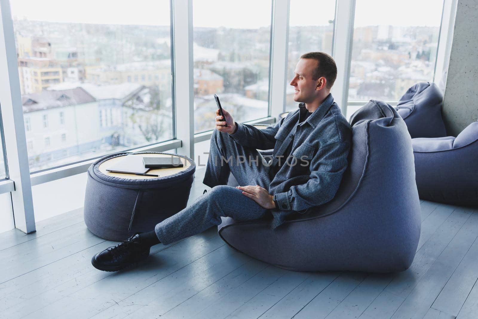 Confident male manager sitting in a modern workspace at a laptop and talking on the phone, remote work