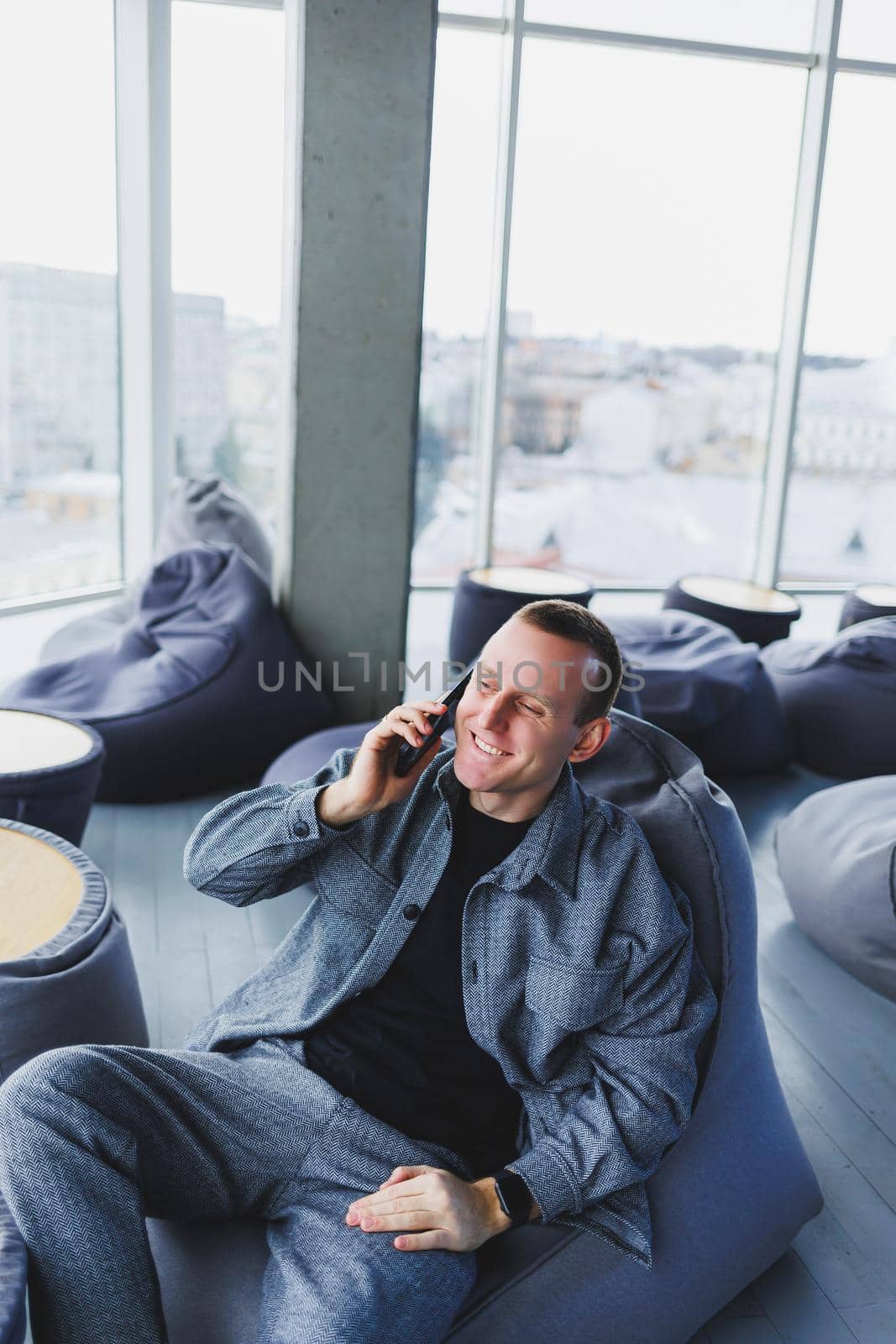 Confident male manager sitting in a modern workspace at a laptop and talking on the phone, remote work