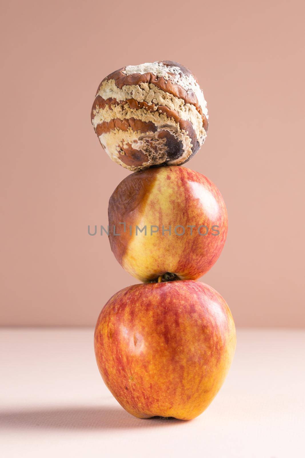 Apple with mold and fresh apple on beige background - mold growth and food spoilage concept