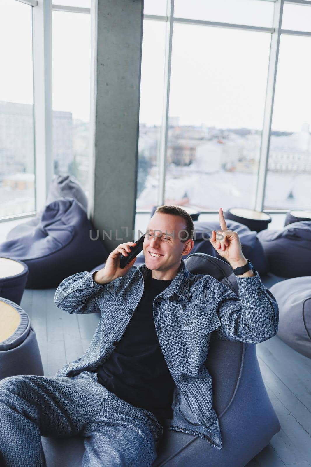 Confident male manager sitting in a modern workspace at a laptop and talking on the phone, remote work
