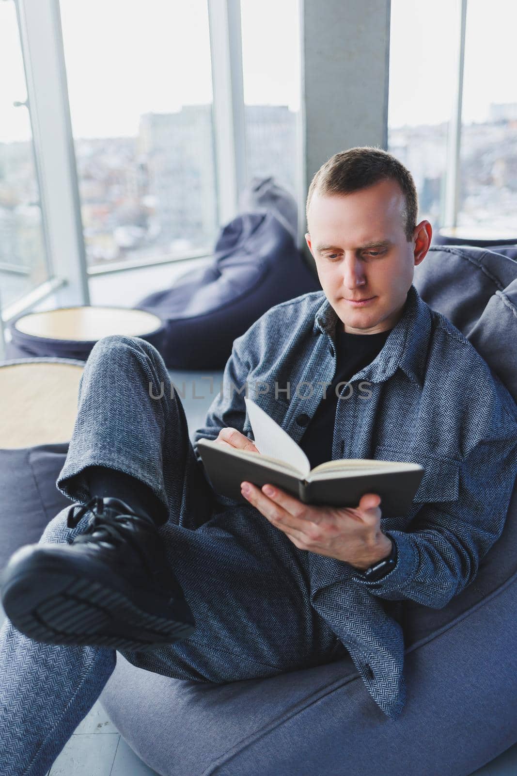 A male businessman in a casual suit resting in a comfortable pouf while working, an attractive freelancer in a suit works remotely and checks notes in a notebook
