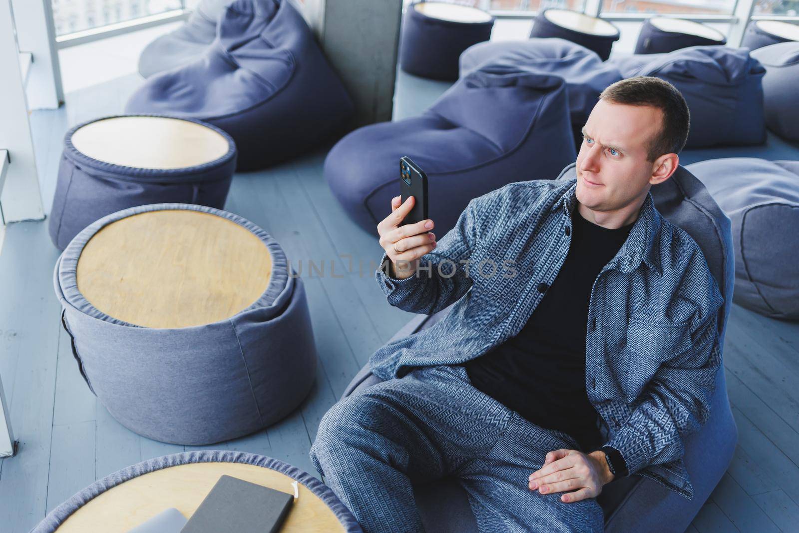 Excited young man in suit using mobile phone with funny expression, excited business man looking at his smartphone, reading good news via email, emotional lifestyle concept.