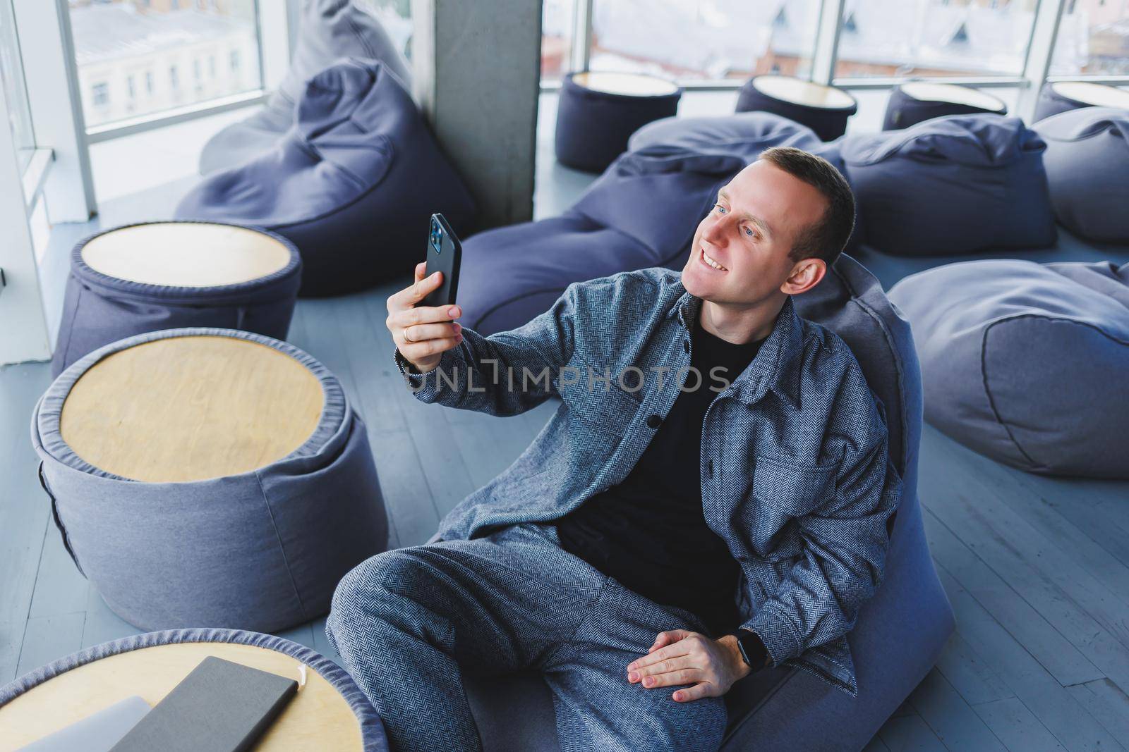 Excited young man in suit using mobile phone with funny expression, excited business man looking at his smartphone, reading good news via email, emotional lifestyle concept.