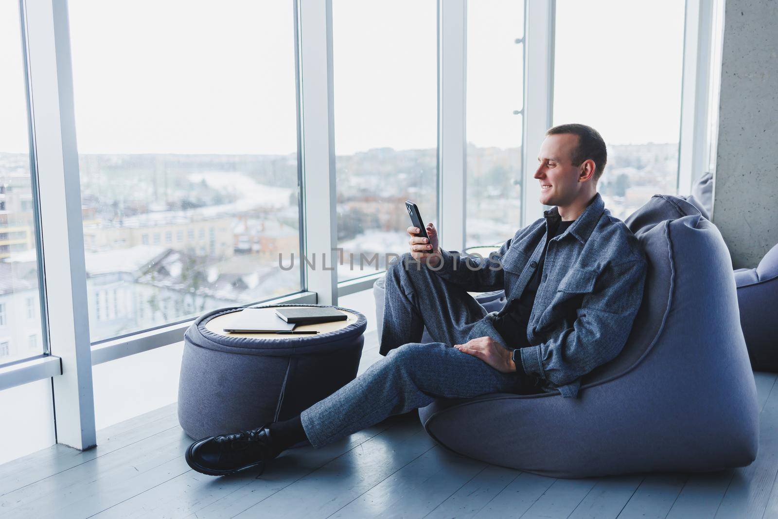 Confident male manager sitting in a modern workspace at a laptop and talking on the phone, remote work