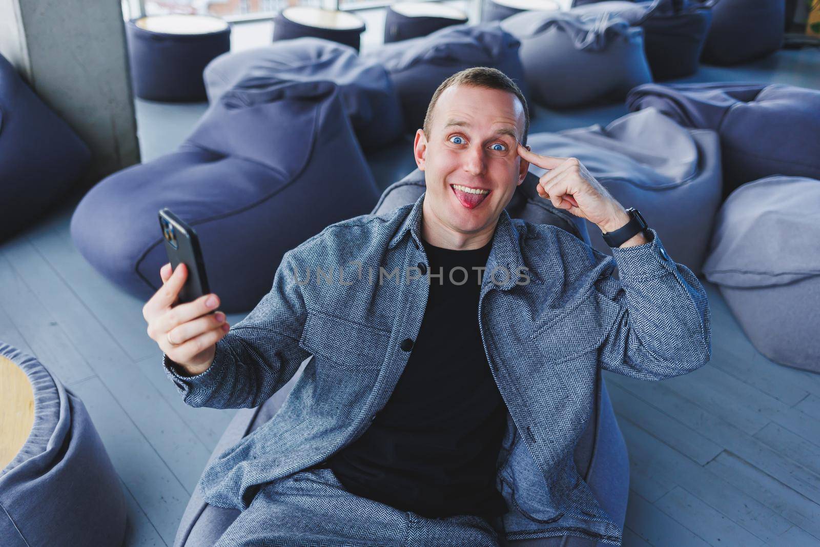 Excited young man in suit using mobile phone with funny expression, excited business man looking at his smartphone, reading good news via email, emotional lifestyle concept.