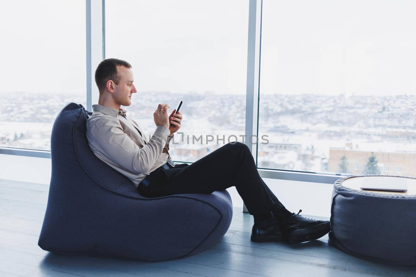 A businessman communicates with his clients by phone while sitting in a modern office workspace. Focused businessman sits alone in a modern workspace.