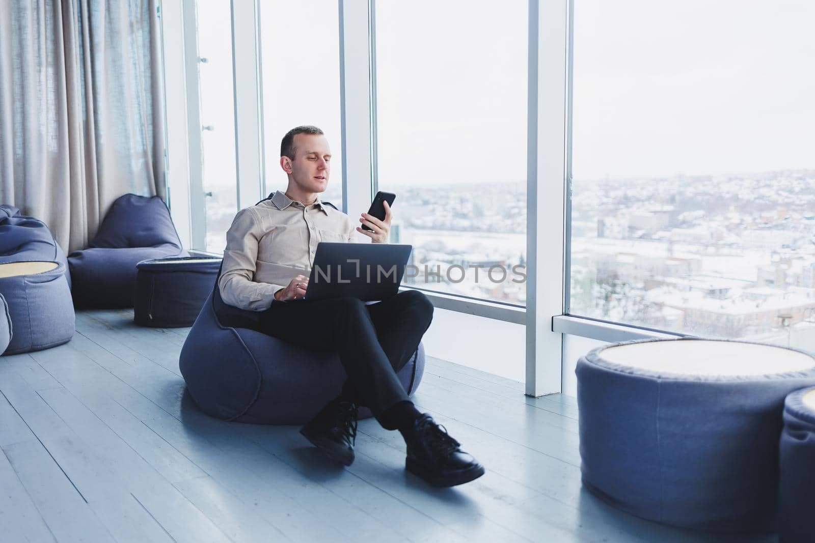 Concentrated young businessman looking at laptop screen, information online or working remotely online at home office, communicating remotely with client or study.