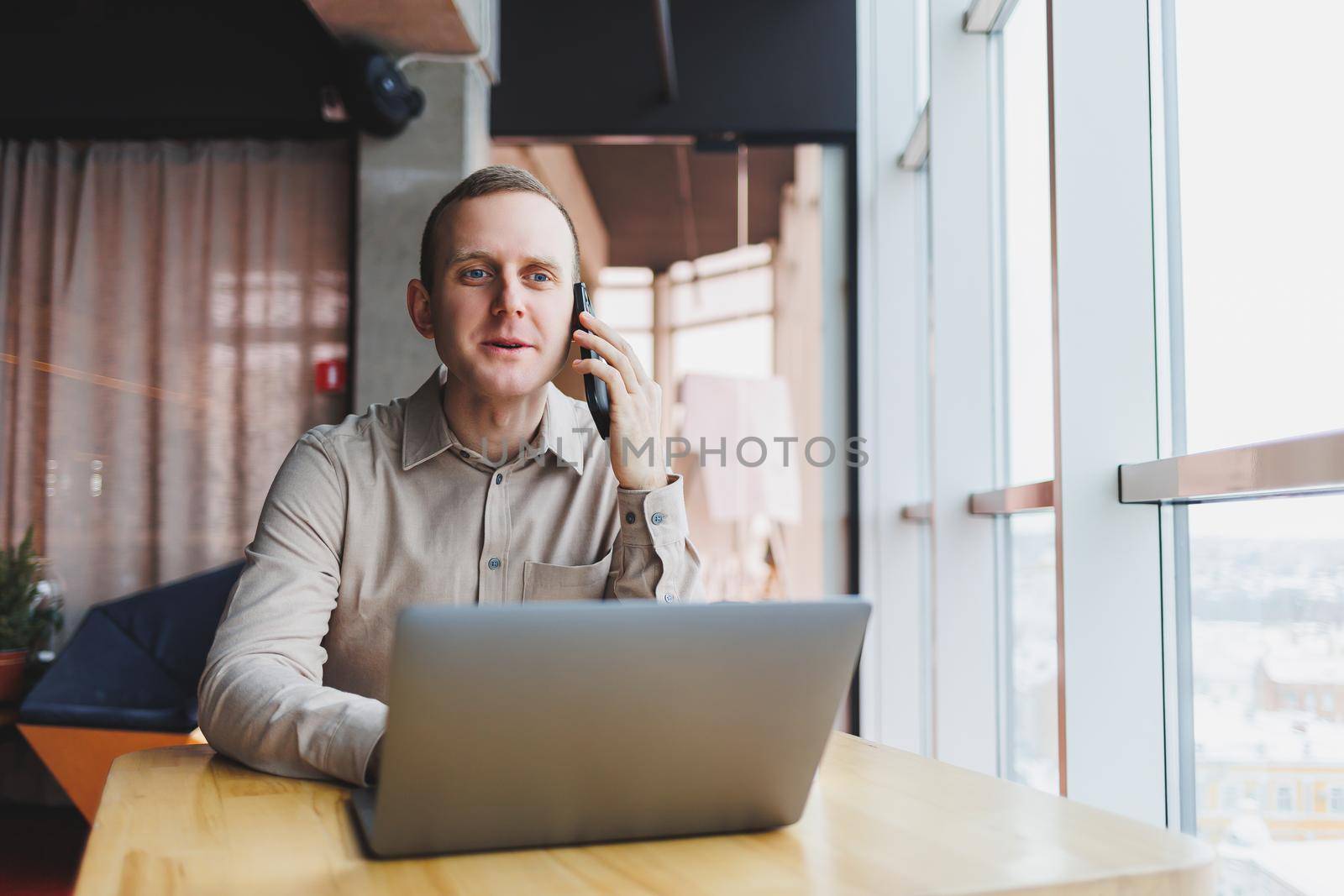 A successful businessman sits in a working cafe and works on an important project. Businessman is typing on a laptop. Businessman using laptop in cafe