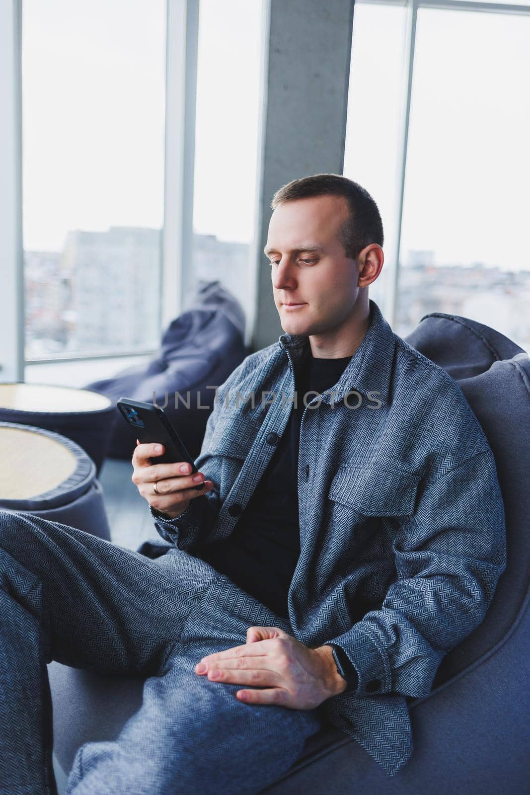 Confident male manager sitting in a modern workspace at a laptop and talking on the phone, remote work