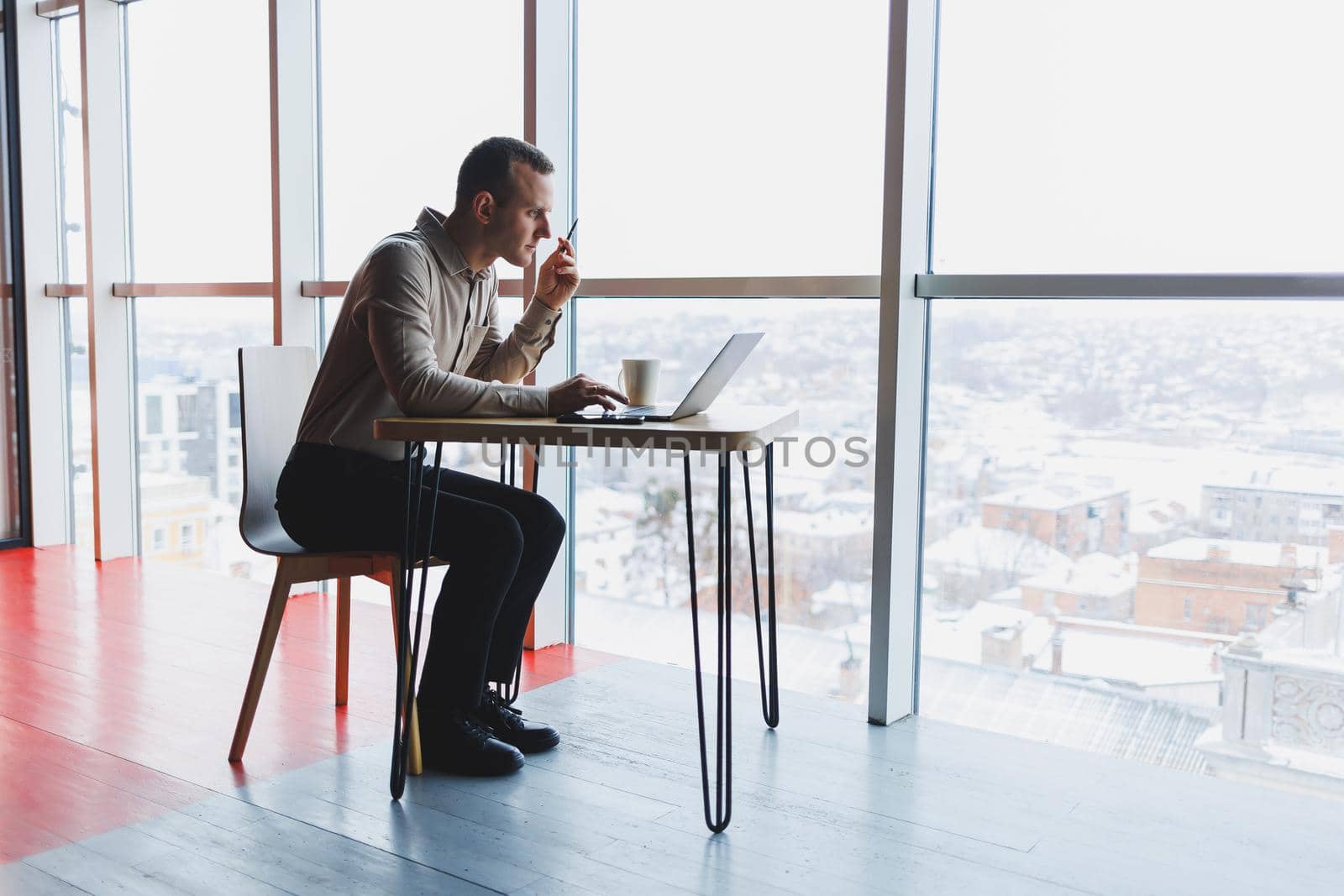 Smart young man looking for information on a website and working as a freelancer on developing a graphic project on a modern laptop using a wireless internet connection in a cafe interior