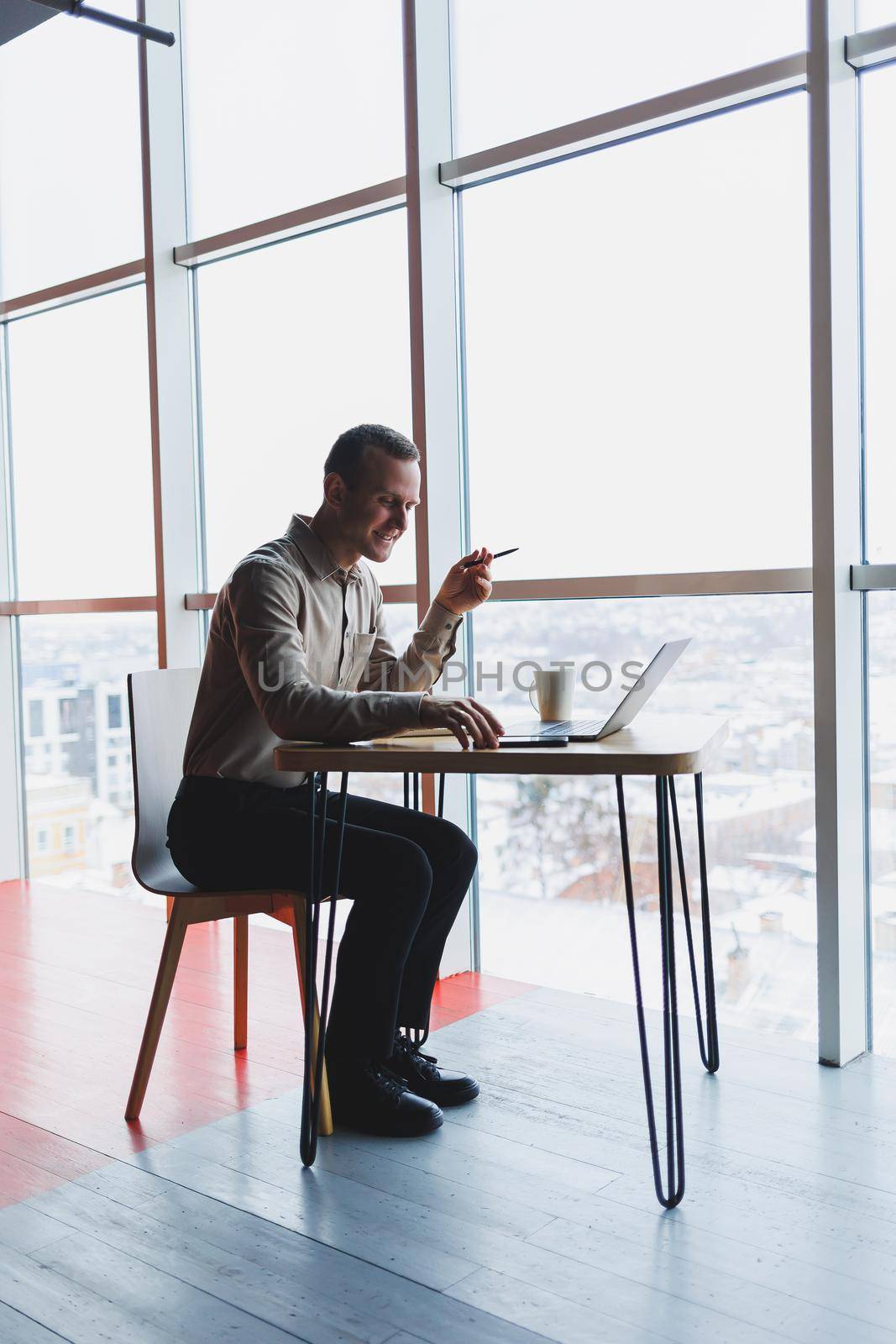 Smart young man looking for information on a website and working as a freelancer on developing a graphic project on a modern laptop using a wireless internet connection in a cafe interior