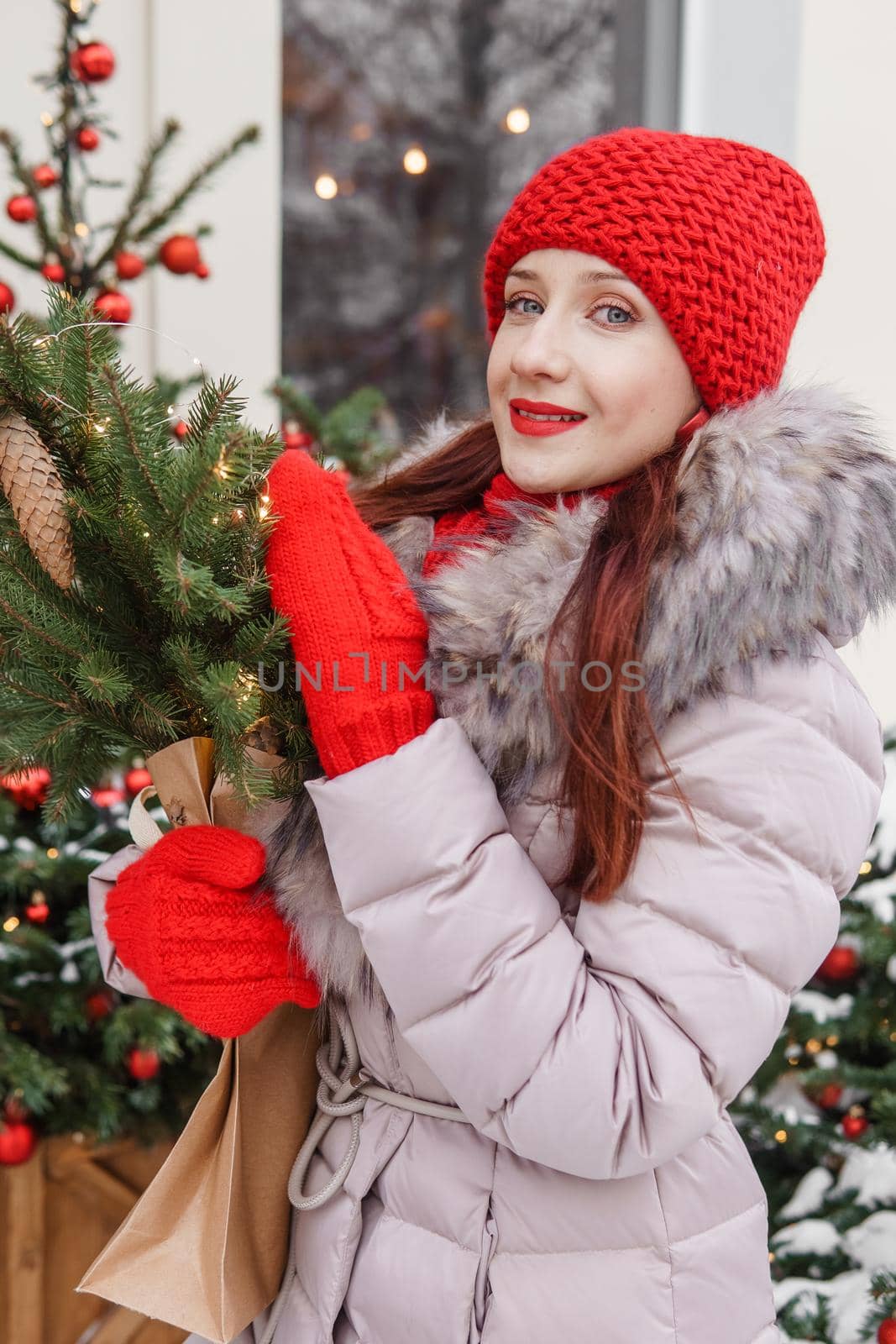 A bright woman in winter clothes walks around the city decorated for Christmas. Lifestyle in the winter season.
