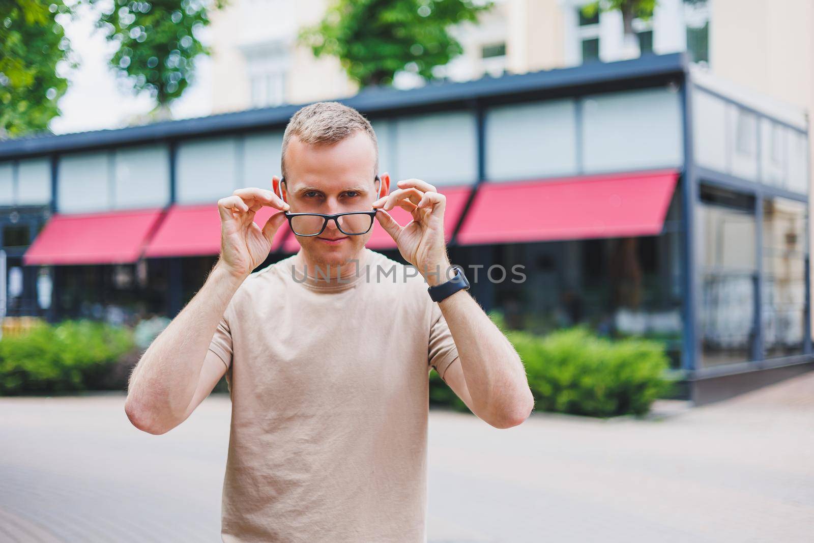 Happy african casual man in glasses sits at cafe table looking at camera, cheerful black student posing studying with book in coffee house, smiling businessman works on laptop in cafeteria, portrait