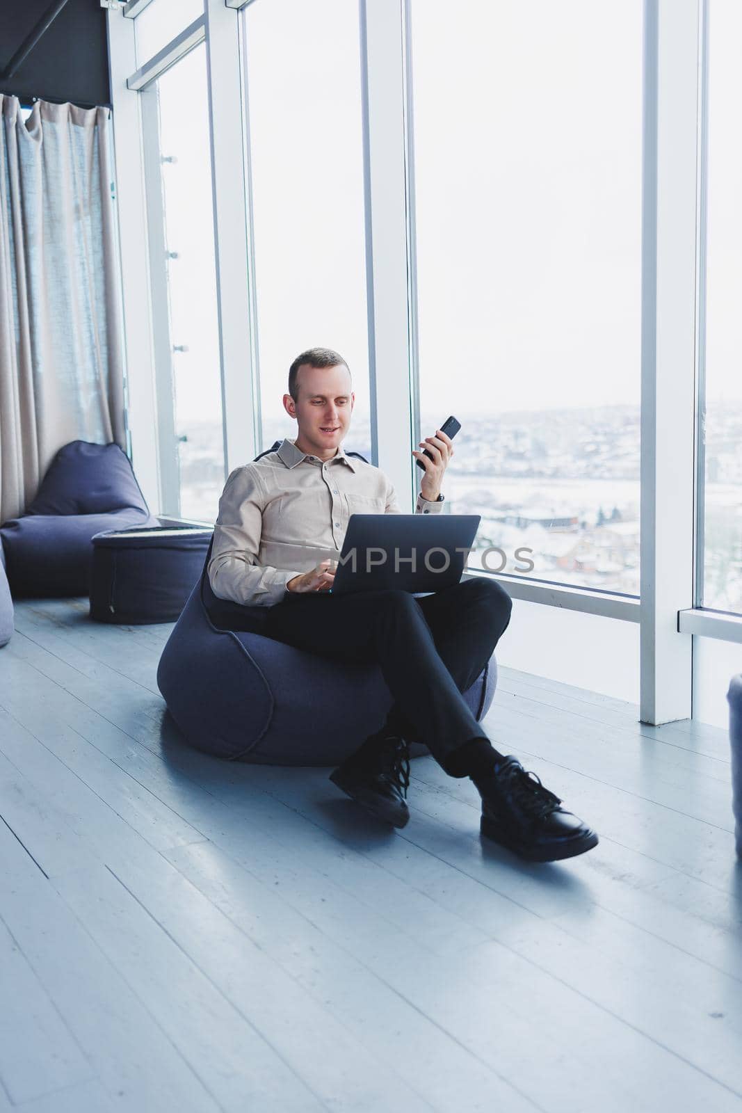 Concentrated young businessman looking at laptop screen, information online or working remotely online at home office, communicating remotely with client or study.