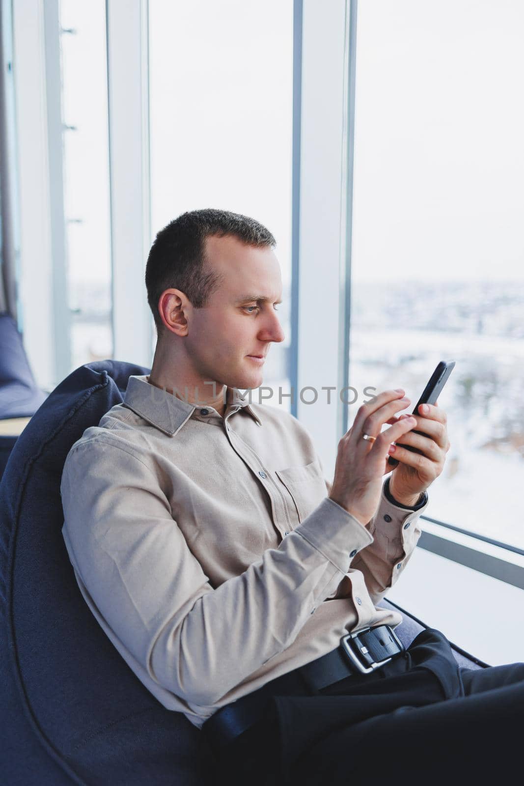 A businessman communicates with his clients by phone while sitting in a modern office workspace. Focused businessman sits alone in a modern workspace.