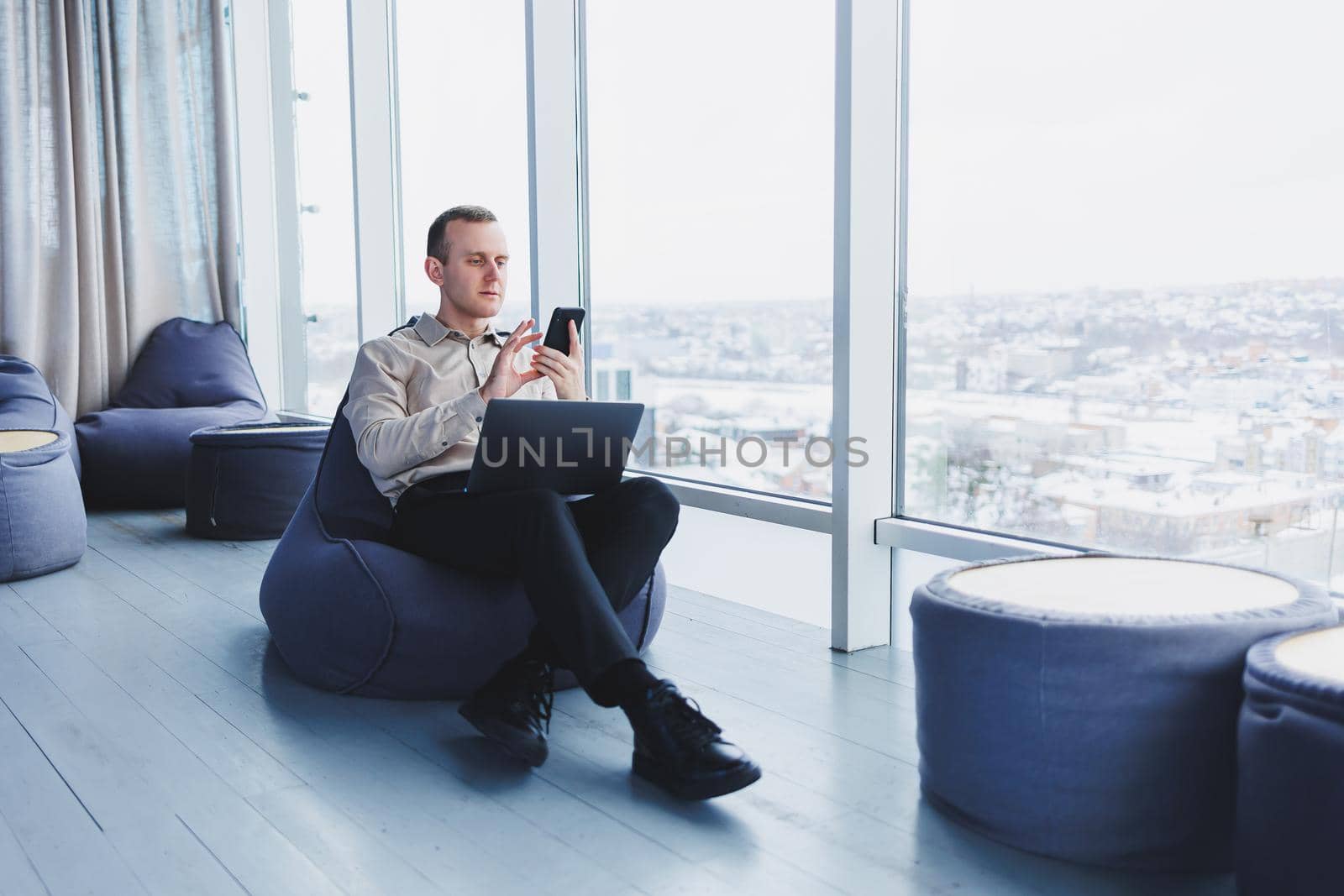 Concentrated young businessman looking at laptop screen, information online or working remotely online at home office, communicating remotely with client or study.