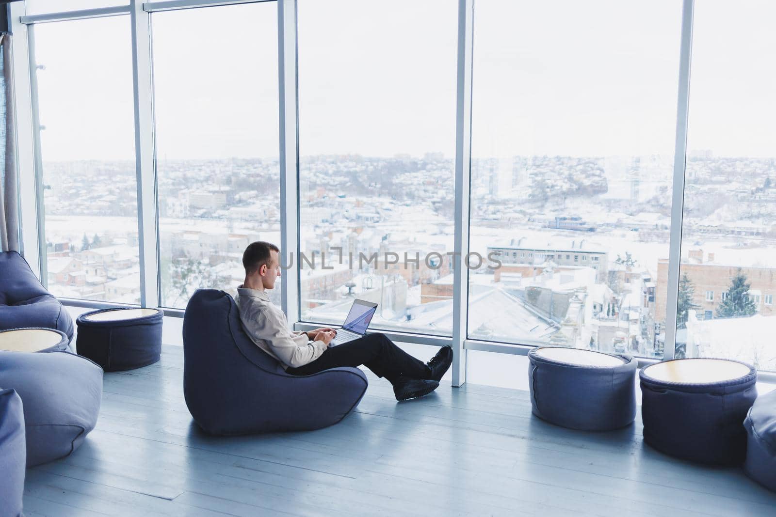 Concentrated young businessman looking at laptop screen, information online or working remotely online at home office, communicating remotely with client or study.