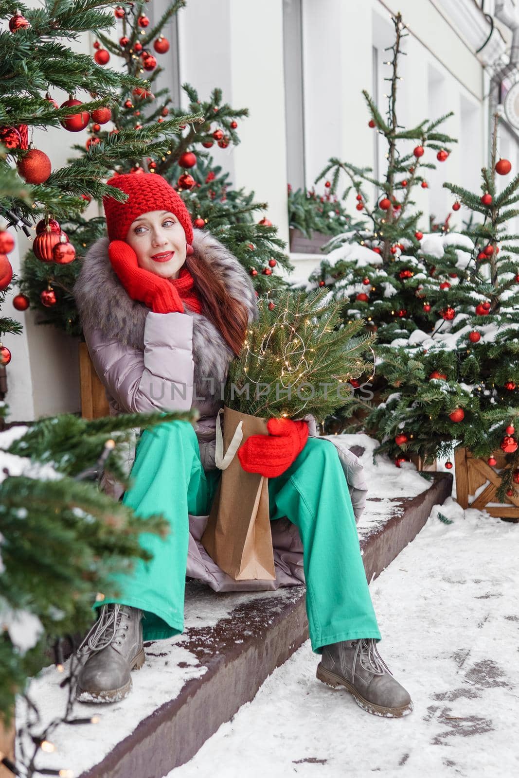 A bright woman in winter clothes walks around the city decorated for Christmas. Lifestyle in the winter season.