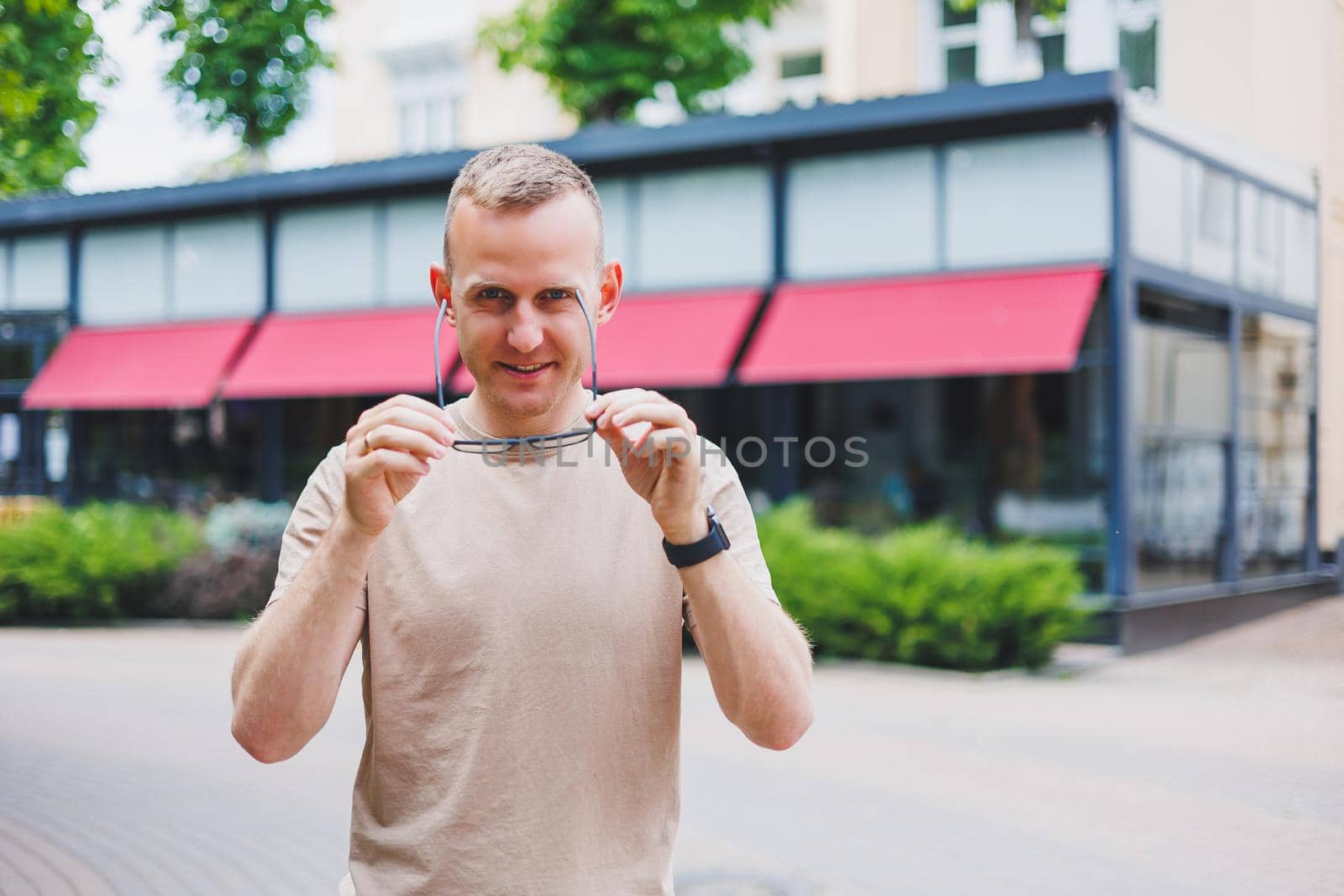Happy african casual man in glasses sits at cafe table looking at camera, cheerful black student posing studying with book in coffee house, smiling businessman works on laptop in cafeteria, portrait