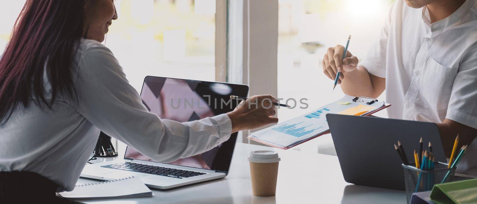 Close up of diverse businesspeople group discussing charts and graphs on meeting, multiethnic team of corporate managers or employees analyzing information materials hardcopy in office together