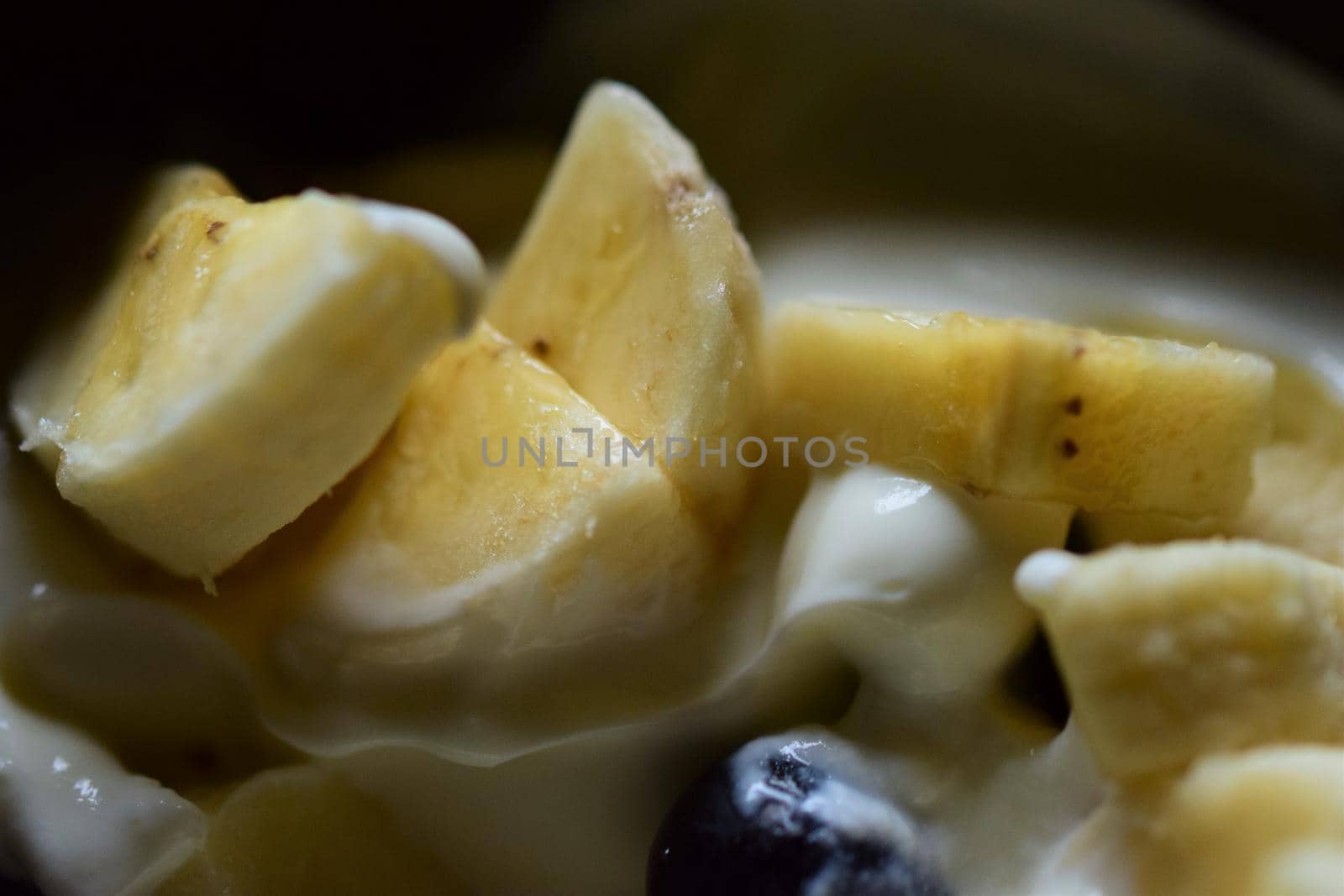 Close-up of pieces of banana and a blueberry in yoghurt